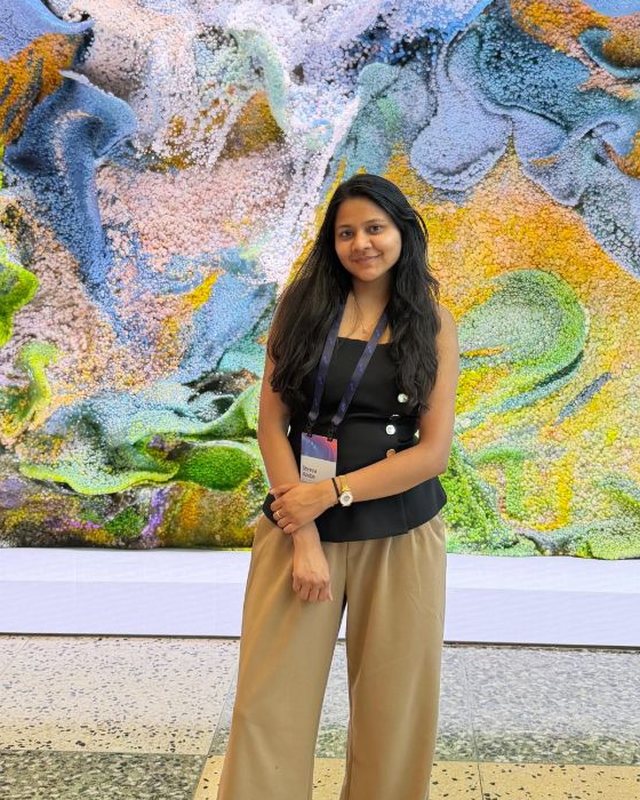Shreya Asoba standing in front of a colourful digital art wall